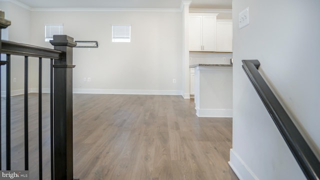 interior space featuring baseboards, light wood-style floors, and crown molding