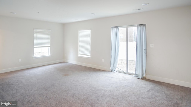 carpeted spare room with visible vents and baseboards