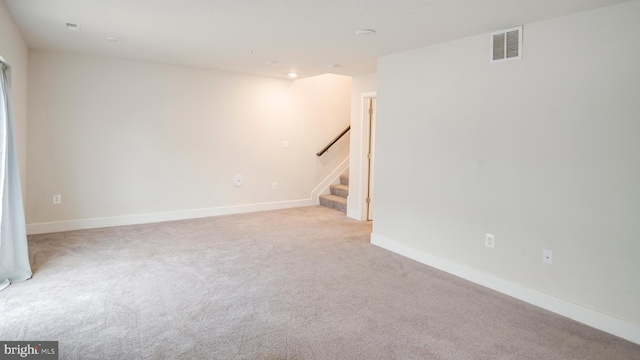 carpeted empty room with stairway, visible vents, and baseboards