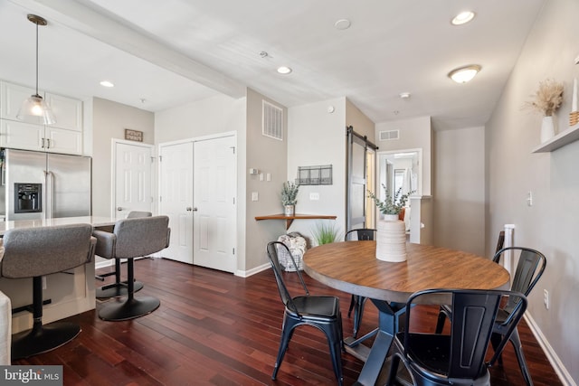 dining space featuring a barn door, baseboards, visible vents, and dark wood finished floors