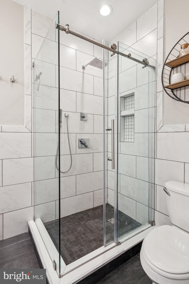 full bath with a shower stall, toilet, and tile walls