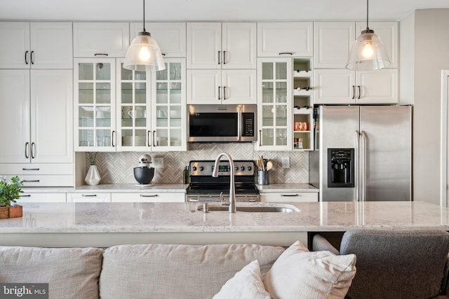 kitchen with tasteful backsplash, white cabinets, and appliances with stainless steel finishes