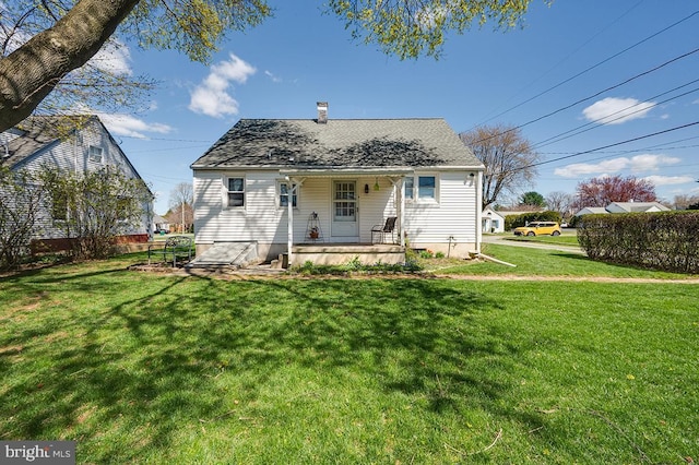 back of house with a yard, a porch, and a chimney