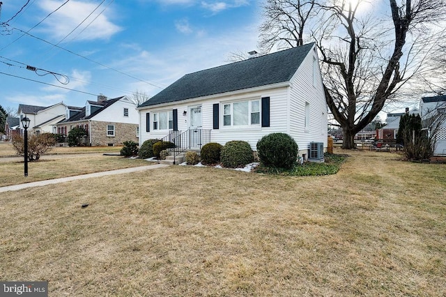 view of front of home featuring a shingled roof, central AC, and a front yard