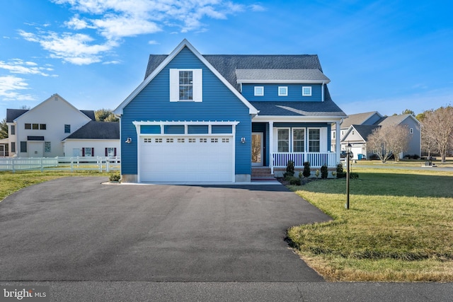 view of front of property featuring covered porch, fence, aphalt driveway, and a front yard