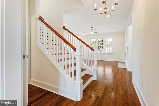 staircase with ceiling fan with notable chandelier, recessed lighting, baseboards, and hardwood / wood-style flooring