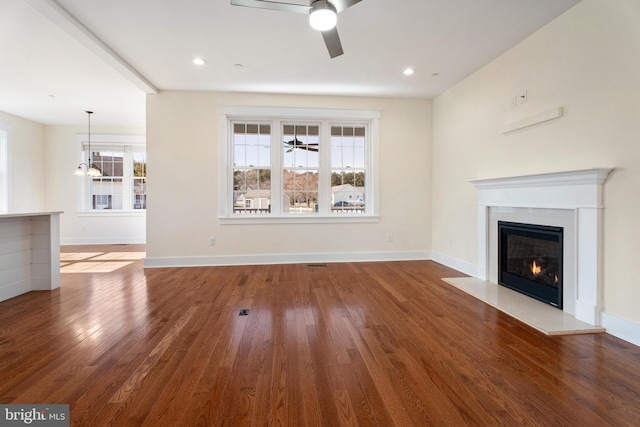 unfurnished living room featuring a ceiling fan, baseboards, hardwood / wood-style floors, and a glass covered fireplace