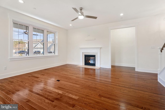 unfurnished living room featuring a fireplace with flush hearth, recessed lighting, dark wood finished floors, and baseboards