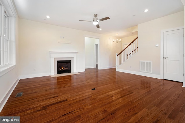 unfurnished living room with dark wood-style flooring, a fireplace with flush hearth, visible vents, and baseboards