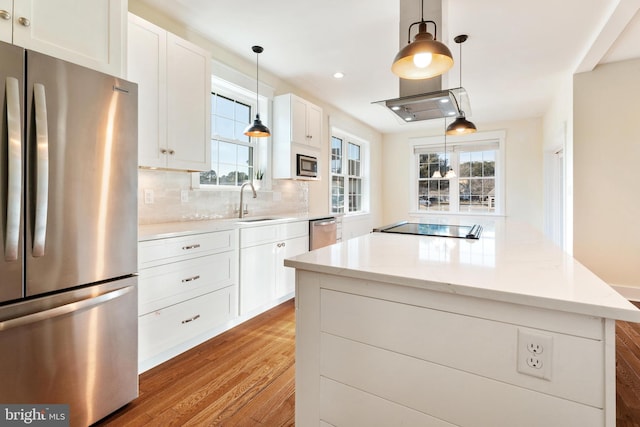 kitchen featuring white cabinets, wood finished floors, decorative light fixtures, light stone countertops, and stainless steel appliances