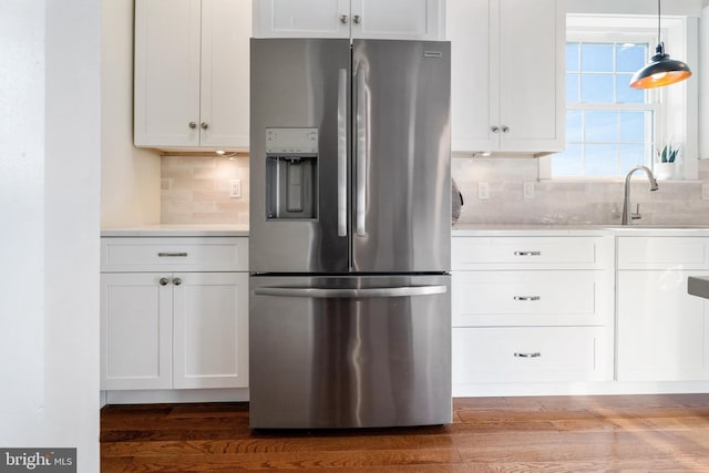 kitchen with light countertops, hanging light fixtures, stainless steel refrigerator with ice dispenser, and white cabinetry