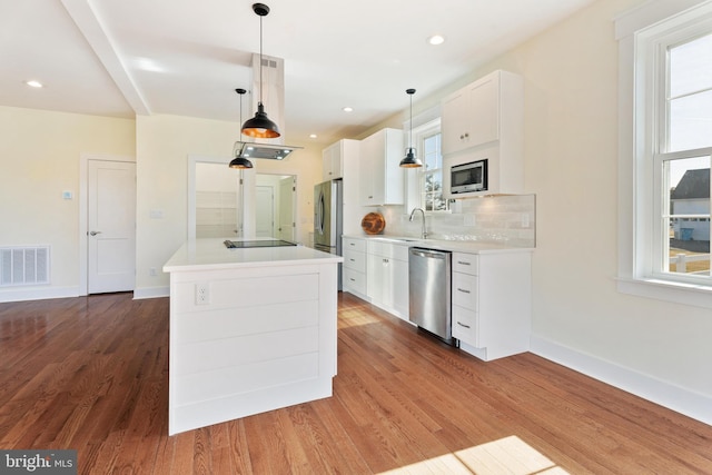 kitchen featuring stainless steel appliances, light countertops, visible vents, hanging light fixtures, and white cabinets