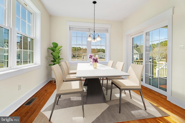 dining space with baseboards, wood finished floors, visible vents, and a healthy amount of sunlight