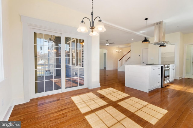 kitchen with wood finished floors, white cabinetry, stainless steel range with electric cooktop, island exhaust hood, and decorative light fixtures