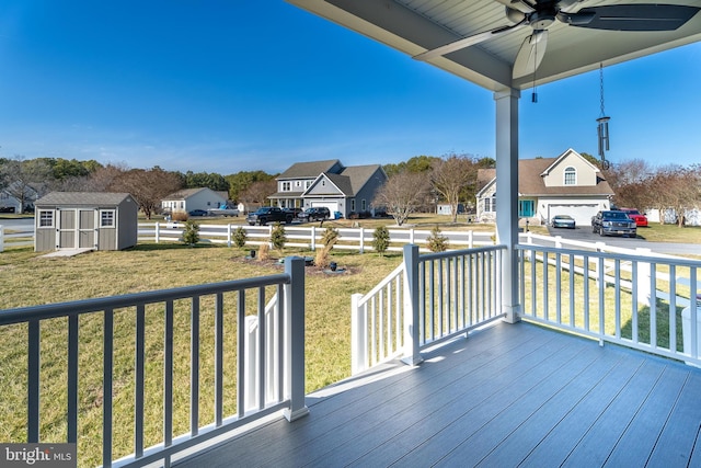 deck featuring a yard, an outdoor structure, a residential view, and a ceiling fan