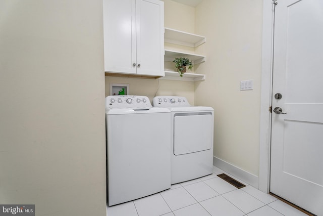 clothes washing area featuring cabinet space, light tile patterned floors, visible vents, baseboards, and washing machine and dryer