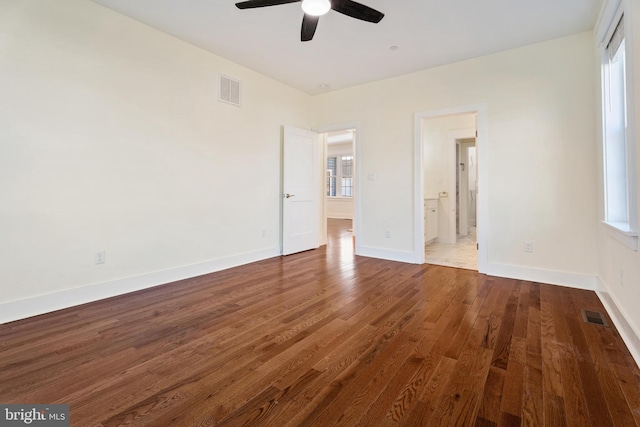 unfurnished bedroom with visible vents, ensuite bathroom, baseboards, and wood finished floors