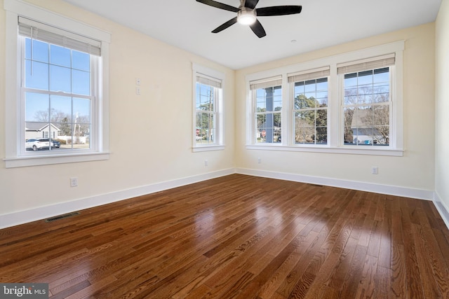 unfurnished room featuring dark wood-type flooring, visible vents, baseboards, and a ceiling fan