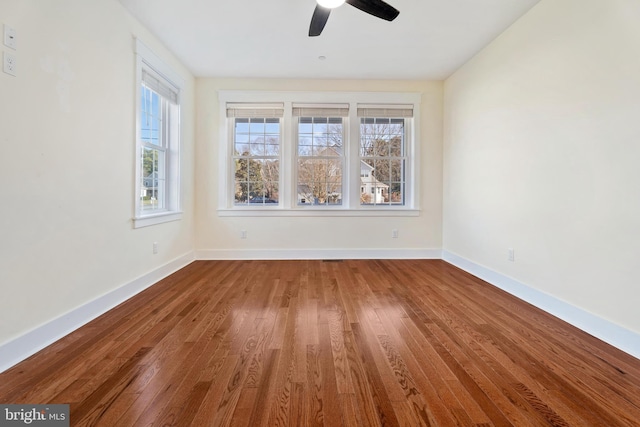 spare room featuring a ceiling fan, baseboards, and wood finished floors