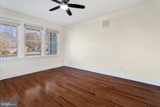 empty room with dark wood-style floors, ceiling fan, visible vents, and baseboards