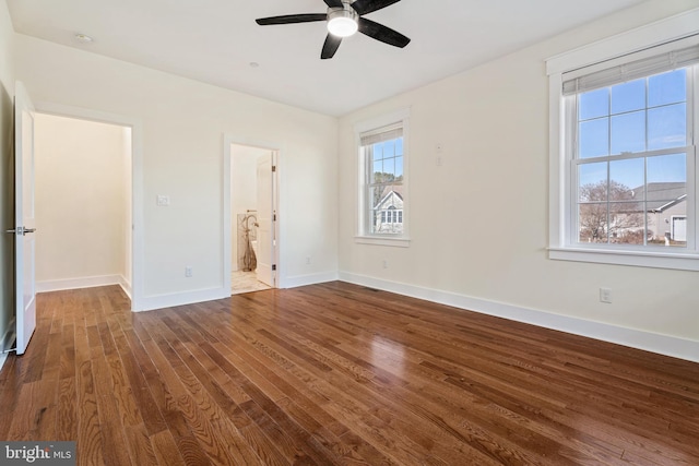 unfurnished bedroom featuring dark wood-style floors, multiple windows, and baseboards