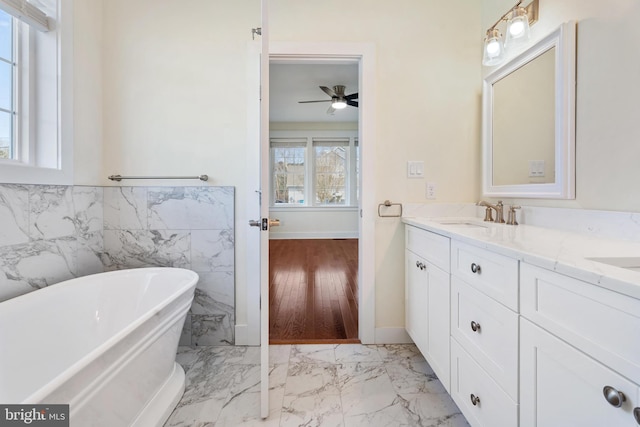 bathroom featuring a freestanding tub, a sink, tile walls, marble finish floor, and double vanity