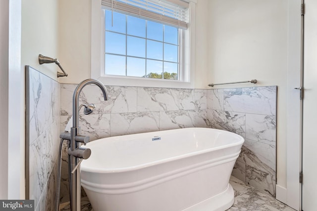 full bathroom with a freestanding tub, marble finish floor, and wainscoting