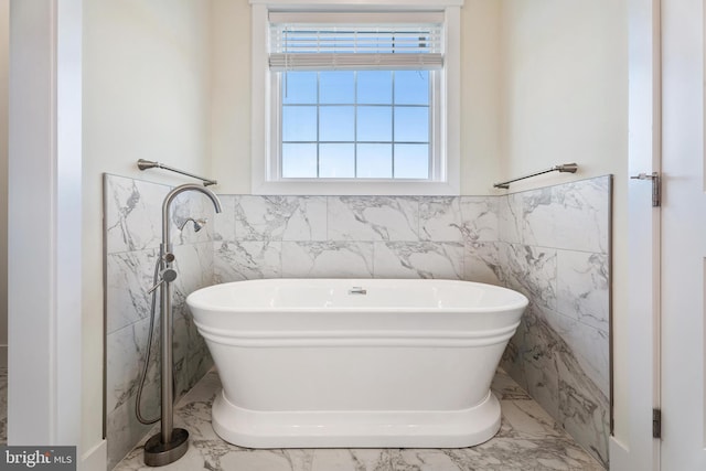 full bath with a freestanding bath, marble finish floor, and a wainscoted wall