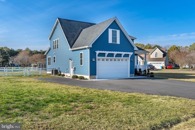 view of home's exterior with aphalt driveway, cooling unit, fence, a yard, and roof with shingles