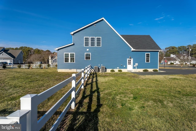 view of home's exterior featuring fence, central AC unit, and a lawn