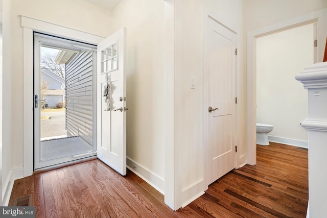 foyer entrance featuring visible vents, baseboards, and wood finished floors