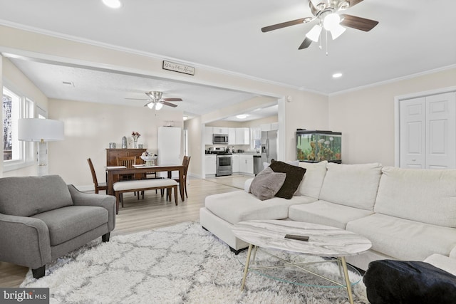 living room with ornamental molding, light wood-type flooring, a ceiling fan, and recessed lighting