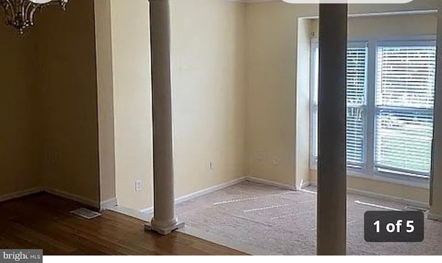 empty room featuring a chandelier, baseboards, and wood finished floors