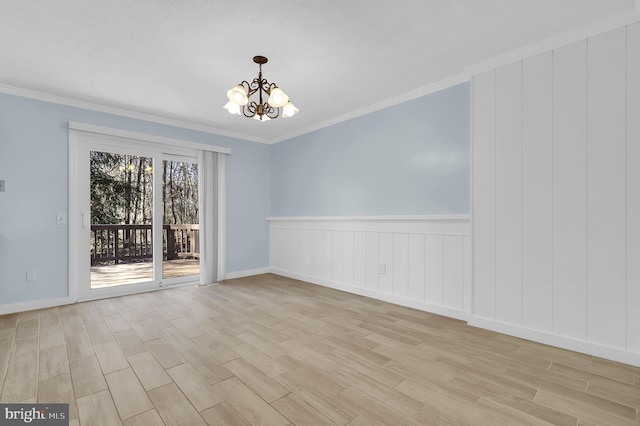 empty room featuring a chandelier, crown molding, and light wood-style floors