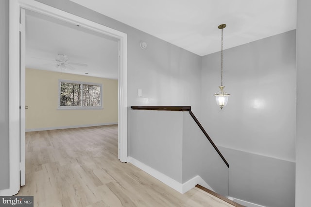 hall featuring baseboards, an upstairs landing, and wood finished floors