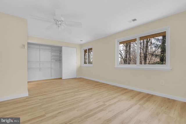 unfurnished bedroom with a closet, visible vents, ceiling fan, wood finished floors, and baseboards