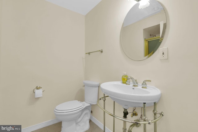 bathroom featuring toilet, baseboards, a sink, and tile patterned floors