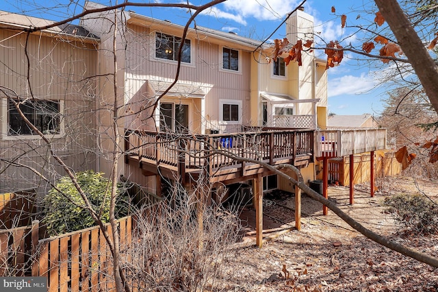 back of house with a deck, central AC unit, and a chimney