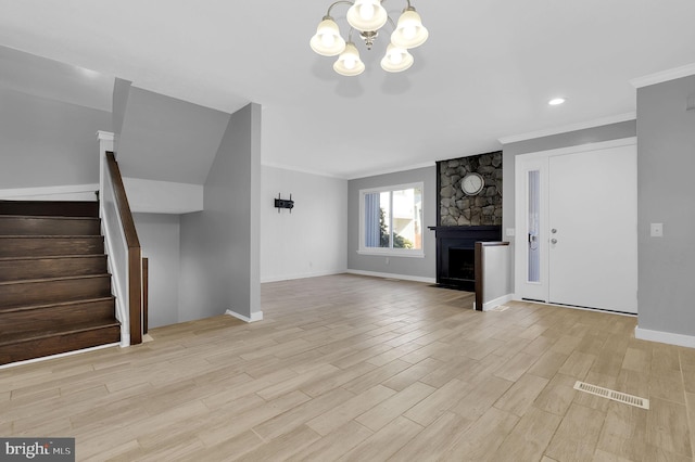 unfurnished living room featuring visible vents, wood finished floors, stairs, crown molding, and a stone fireplace