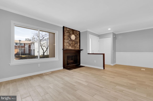 unfurnished living room with crown molding, visible vents, a fireplace, and light wood-style flooring