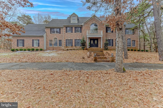 colonial home with brick siding and a balcony