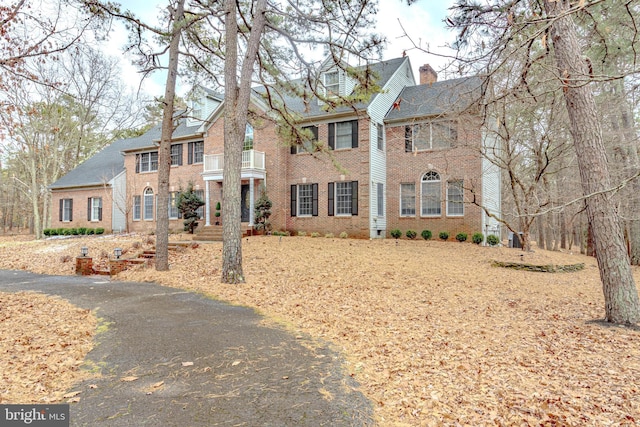 colonial inspired home with a chimney and brick siding