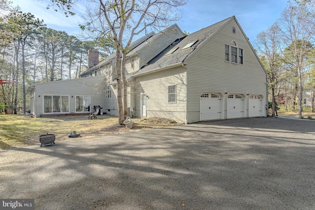 2 Wilderness Dr, Medford, NJ 08055 - view of property exterior with a fire pit, driveway, a chimney, and a garage