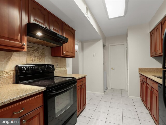 kitchen with light stone counters, under cabinet range hood, electric range, baseboards, and backsplash