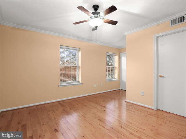 empty room featuring a ceiling fan, baseboards, visible vents, light wood-style floors, and ornamental molding