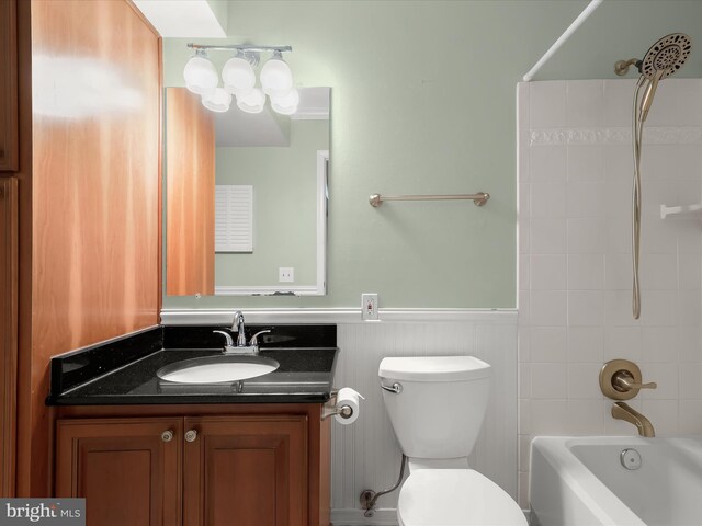 bathroom featuring shower / washtub combination, a wainscoted wall, vanity, and toilet