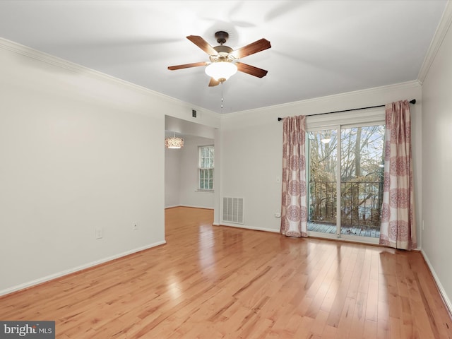 spare room featuring light wood finished floors, plenty of natural light, visible vents, and crown molding