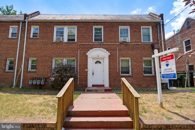 multi unit property featuring a front lawn, cooling unit, and brick siding