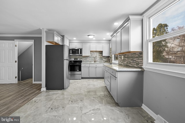 kitchen with tasteful backsplash, baseboards, gray cabinets, stainless steel appliances, and a sink