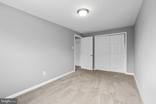 unfurnished bedroom with a closet, baseboards, and carpet